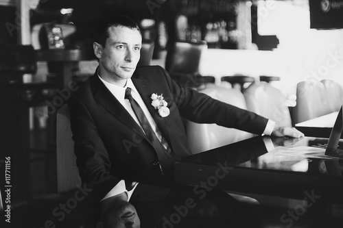 Black and white picture of thoughtful groom sitting at the table