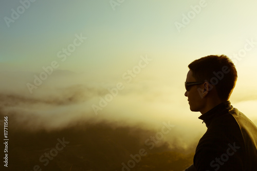 Male hiker above the clouds watching the sun rise.  © kieferpix