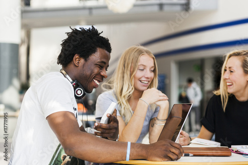 Happy multiethnic friends studying at table in cafe