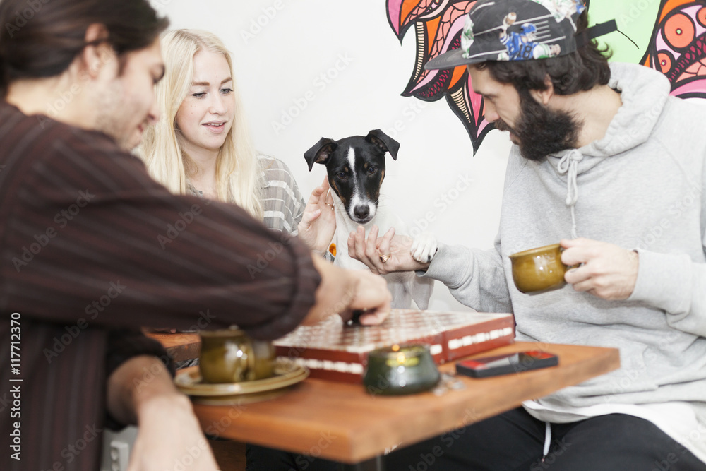 Friends with dog playing dice game at cafe table Friends with dog playing dice game at cafe table
