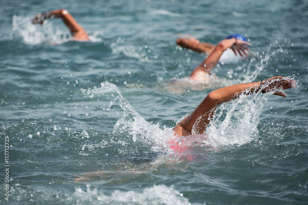 Group of swimmers swim in the sea at the races in triathlon