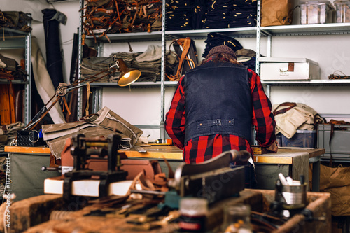 Rear view of male worker working at table in bag factory photo