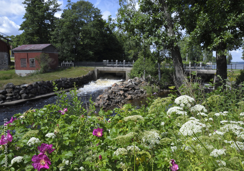 Outlet from a little water power plant and with summer flowers in foreground, picture from the North of Sweden.