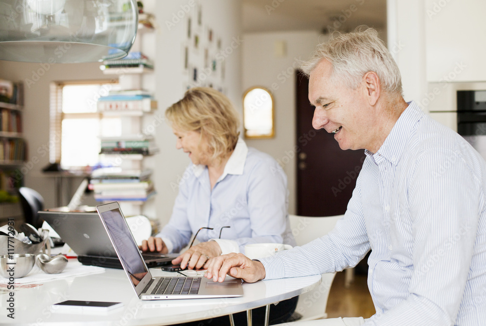 Happy senior business couple using laptops at home Happy senior business couple using laptops at home
