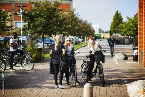 Wallpaper Mural Happy female friends with bicycles standing at college campus Torontodigital.ca