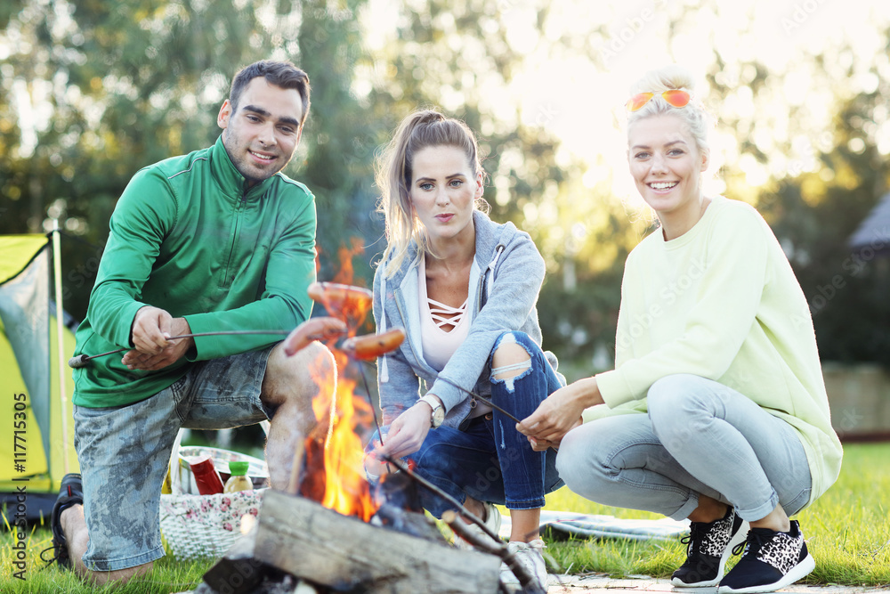 Obraz premium Group of friends preparing marshmallow on campfire