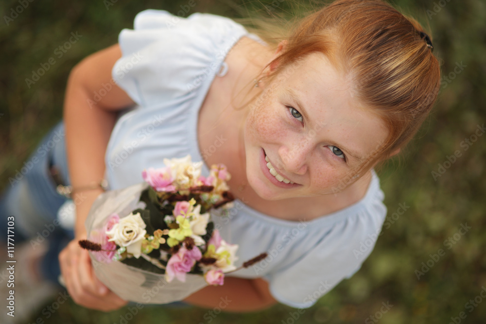 Overhead view of redhair girl holding bouquet of flowers and smiling at the camera Overhead view of redhair girl holding bouquet of flowers and smiling at the camera