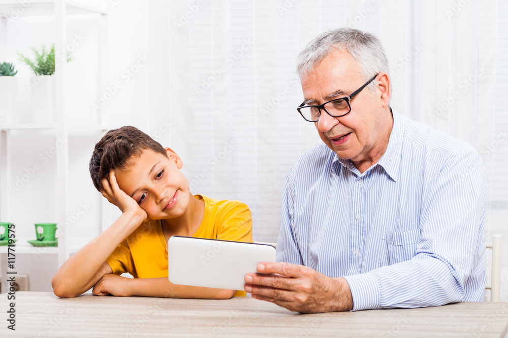 Grandfather and grandson are using tablet at home. Grandfather and grandson are using tablet at home.