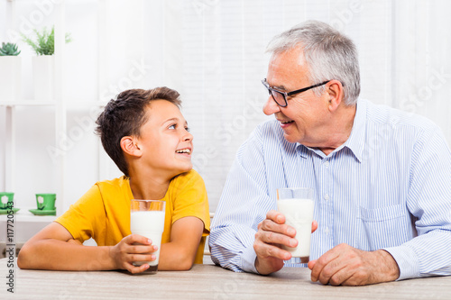 фотографія Grandfather and grandson are drinking milk at home