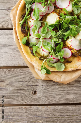 Home Italian pizza with pesto, lettuce and radish on baking pape