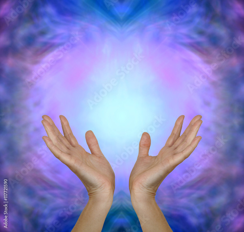 Sensing Angelic Healing Energy - Female hands reaching up into a pink blue Angelic healing energy field with plenty of copy space above