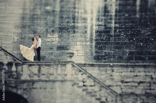 Look from afar on the couple standing on the stone handrails photo