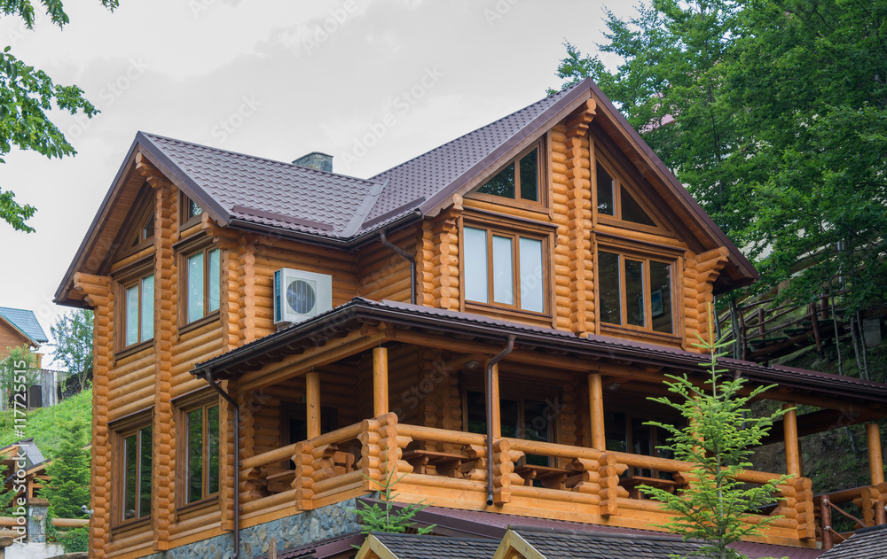 Two-storey wooden round timber house among trees Stock Photo | Adobe Stock