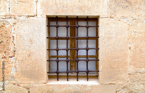 Старый песчаник стены с окном и решеткой