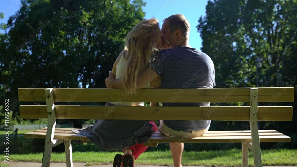 Loving couple kissing on a bench in a city Park Loving couple kissing on a bench in a city Park