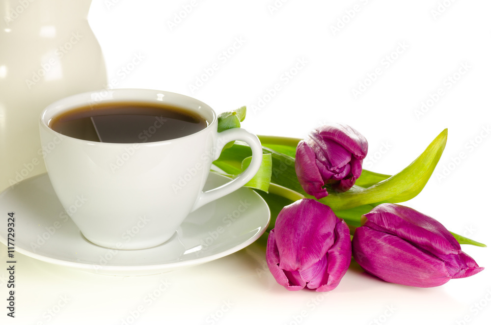 White cup of coffee with bunch of purple tulips on white backgro White cup of coffee with bunch of purple tulips on white backgro
