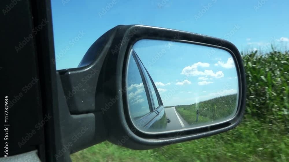 Wing mirror of car driving through corn field on sunny summer day Wing mirror of car driving through corn field on sunny summer day