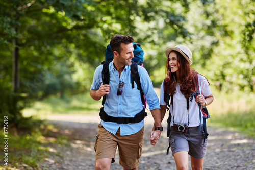 Canvas Print Happy couple hiking together in mountains with backpacks