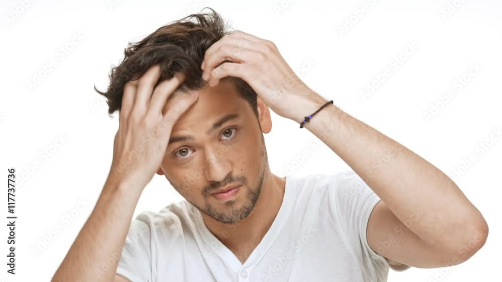 Young handsome man styling hair, looking at camera over white background. Slow motion. Young handsome man styling hair, looking at camera over white background. Slow motion.