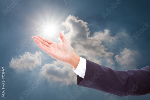 businessman showing something on the open palm in sky