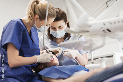 Fototapeta Naklejka Na Ścianę i Meble -  female dentists treating patient girl teeth