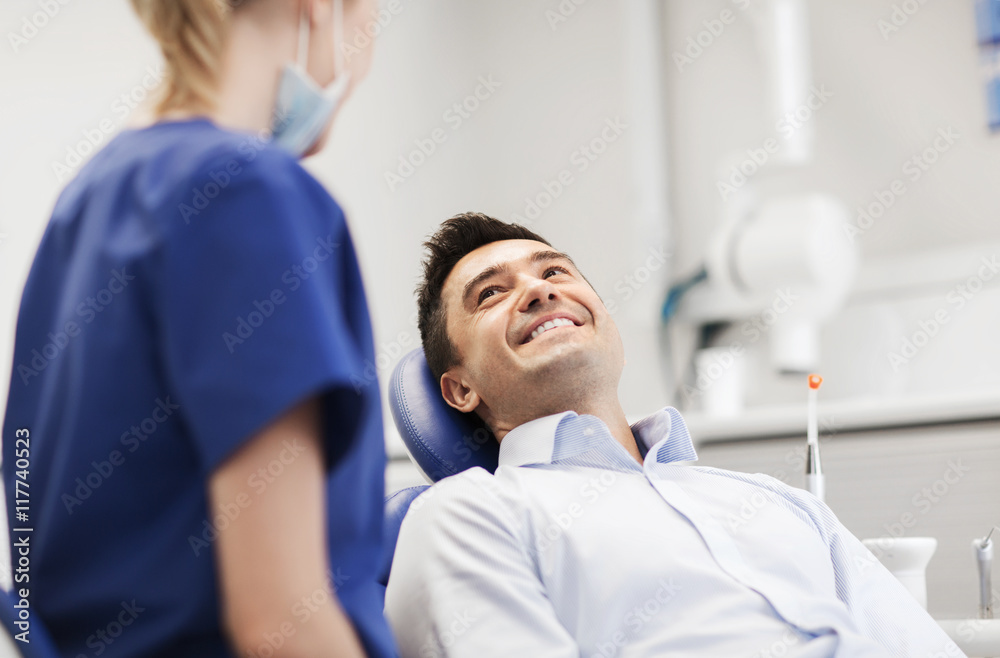 female dentist with happy male patient at clinic - obrazy, fototapety, plakaty 