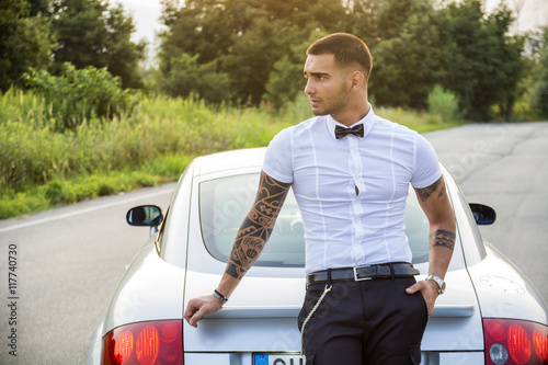 Tableau sur toile Portrait of young attractiave man in white shirt leaning on his new stylish poli