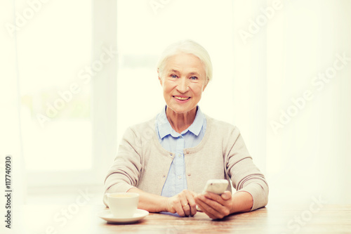 senior woman with smartphone texting at home