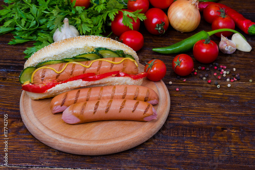 Grilled hot dog with sausage on a background of vegetables