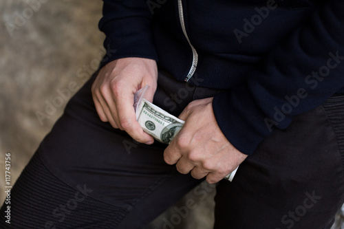 close up of addict or drug dealer hands with money