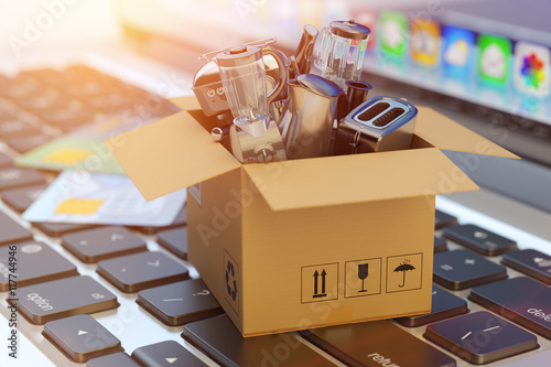 E-commerce, online shopping, internet purchases and goods delivery concept, cardboard box package with household and kitchen appliances on computer laptop keyboard