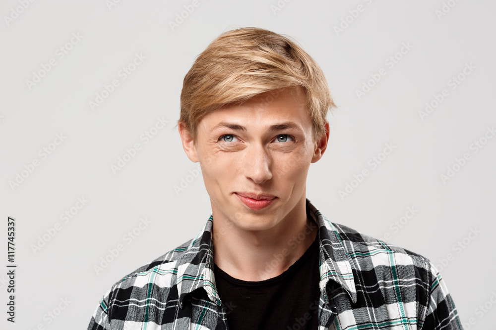Close up portrait of handsome blond young man wearing casual plaid shirt looking away isolated on grey background Close up portrait of handsome blond young man wearing casual plaid shirt looking away isolated on grey background