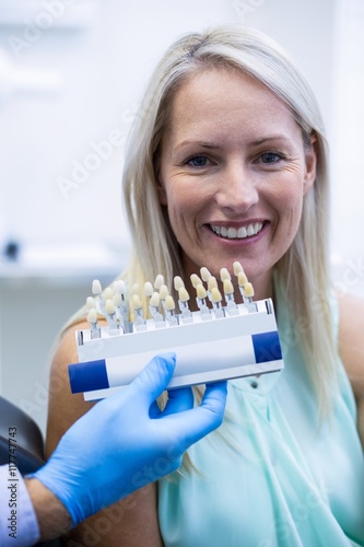 Dentist holding teeth shades while female patient smiling