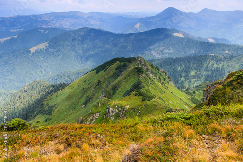 Sunny summer scene in the mountains. View of beautiful landscape of a rocky cliffs and green hills.