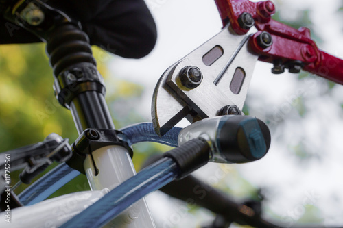 Ein Dieb knackt mit einem Werkzeug ein Fahrradschloss photo