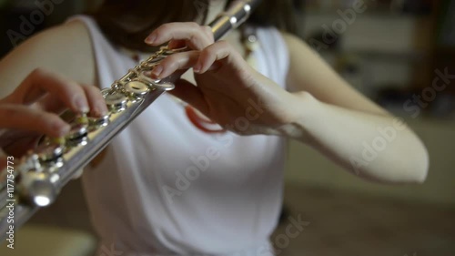 Young girl playing the flute in the living room photo