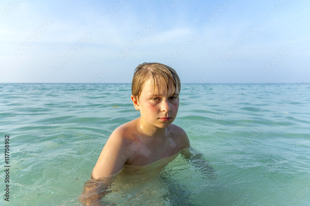 angry young boy walking in the ocean at the beach angry young boy walking in the ocean at the beach