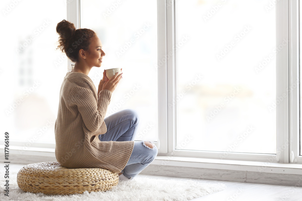 Beautiful African American girl drinking coffee at home