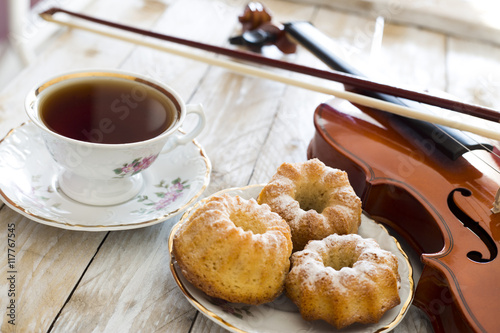 Coffee with cupcakes and violin on the wooden table 