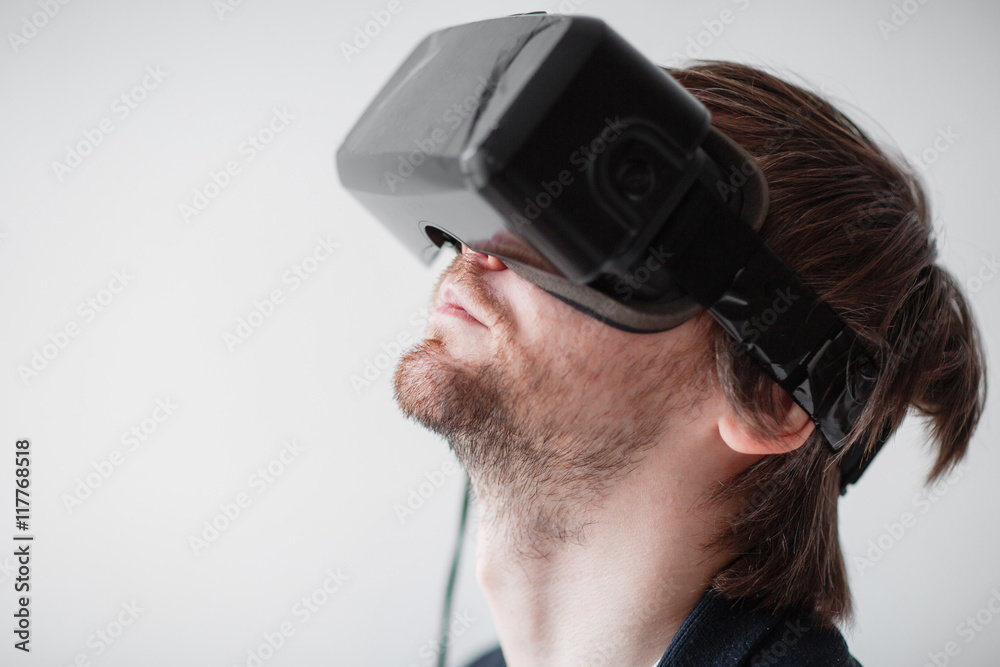 Handsome man wearing virtual reality glasses isolated on a gray background Handsome man wearing virtual reality glasses isolated on a gray background