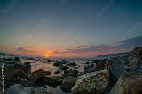 Sunset over the coast with stones. Fish-eye lens