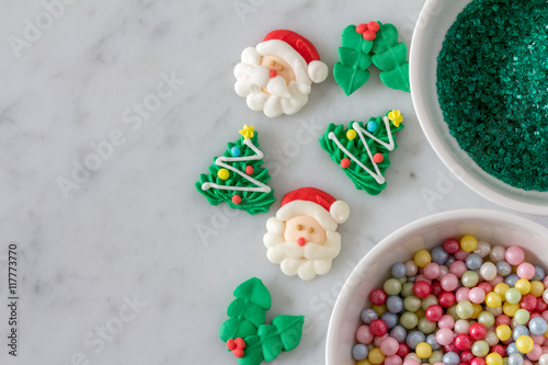 Christmas Baking Decoration set out to Decorate Cookies, with Trees, Santas, Holly, Sprinkles and Sugar Pearls, from Above with Copy Space