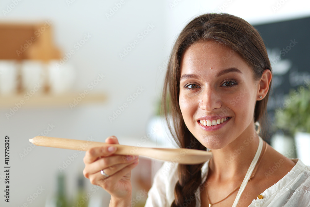 Cooking woman in kitchen with wooden spoon Cooking woman in kitchen with wooden spoon