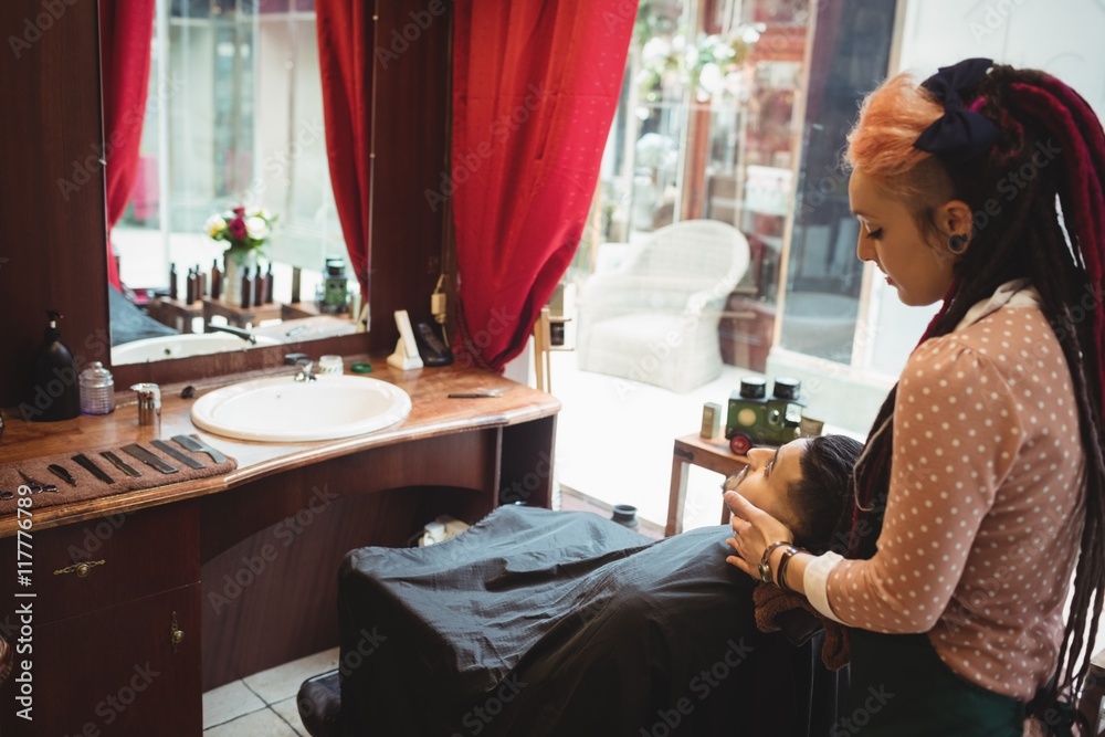 Man receiving a face massage from a female barber Man receiving a face massage from a female barber