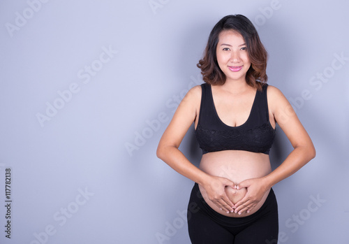 Pregnant Woman holding her hands in a heart shape on belly