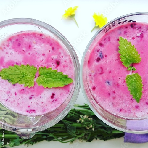 Summer juicy berry smoothie cocktail with mint leaves. Glass of fresh cool berry cocktail and summer sunny mood. Bright and delicious smoothie for a healthy vegan diet and nutrition.