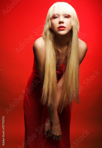 Perfect blond model in red dress over red background.