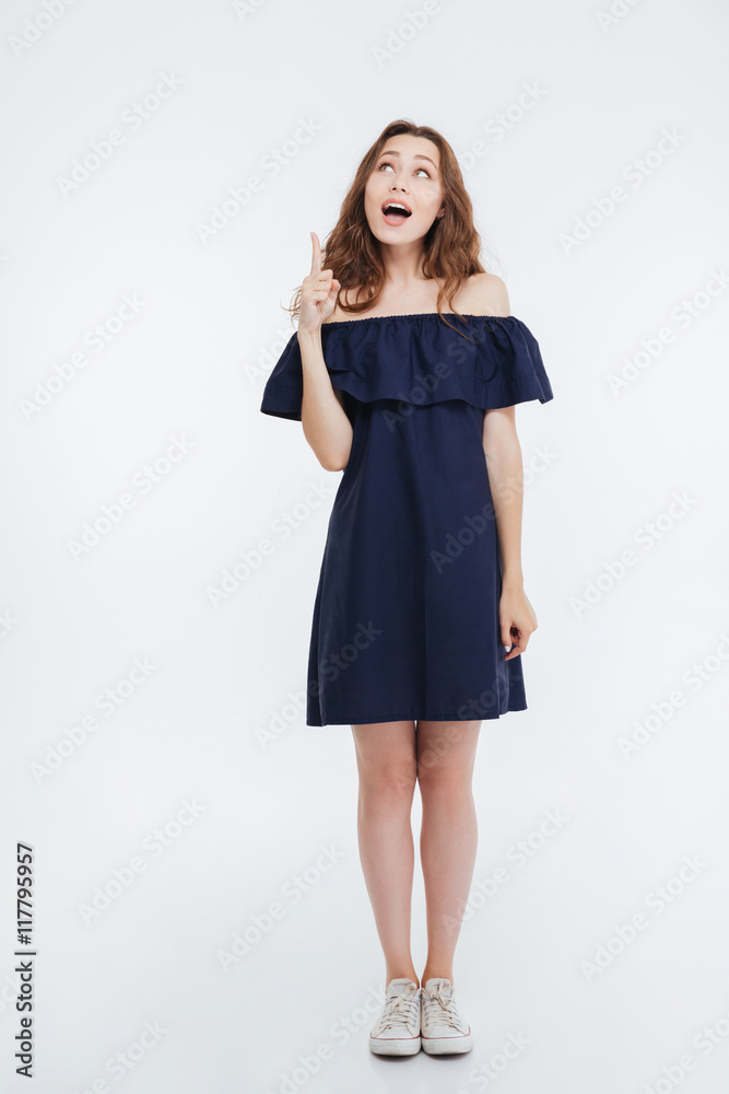 Smiling pretty young woman standing and pointing up Smiling pretty young woman standing and pointing up