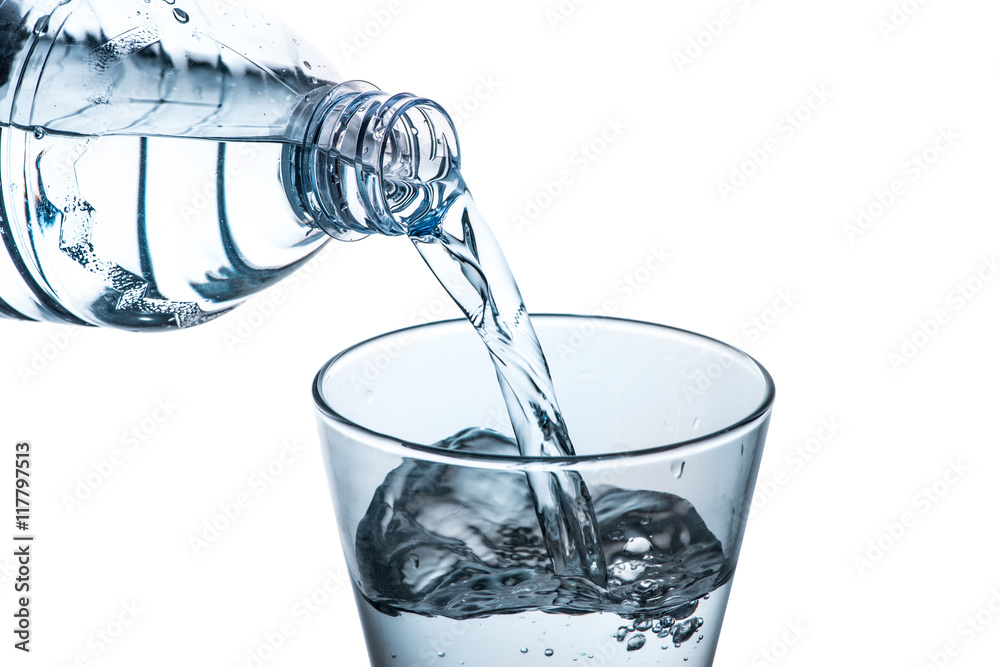 Drinking water is poured into a glass from bottle