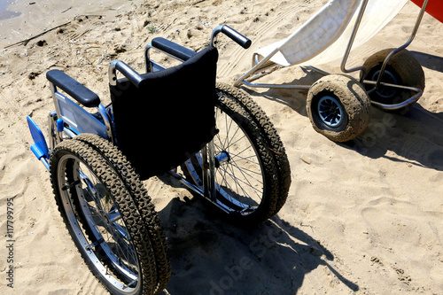 two wheelchairs on the sand of the beach photo